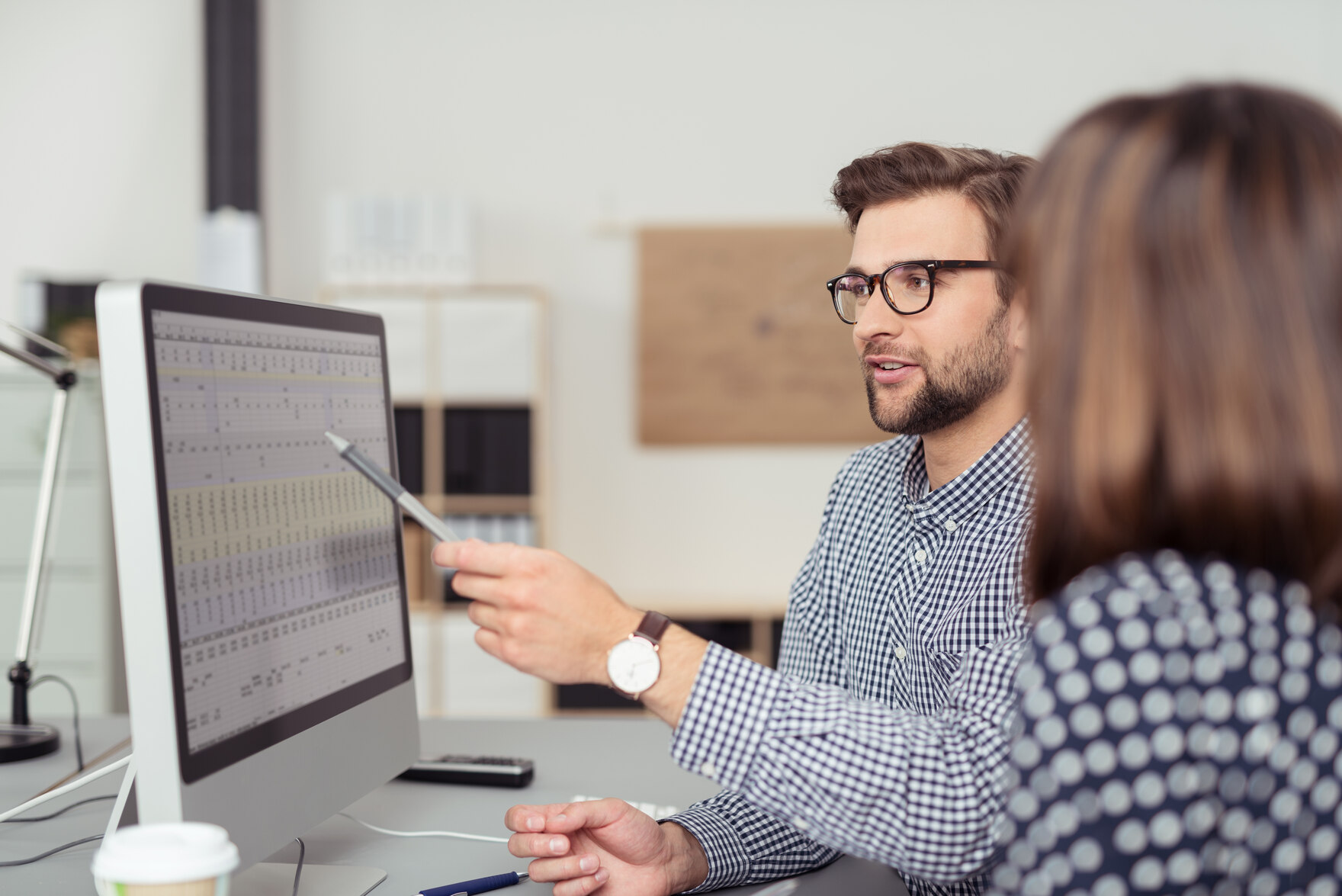 Ein Mann erläutert einer Frau etwas am Computermonitor.