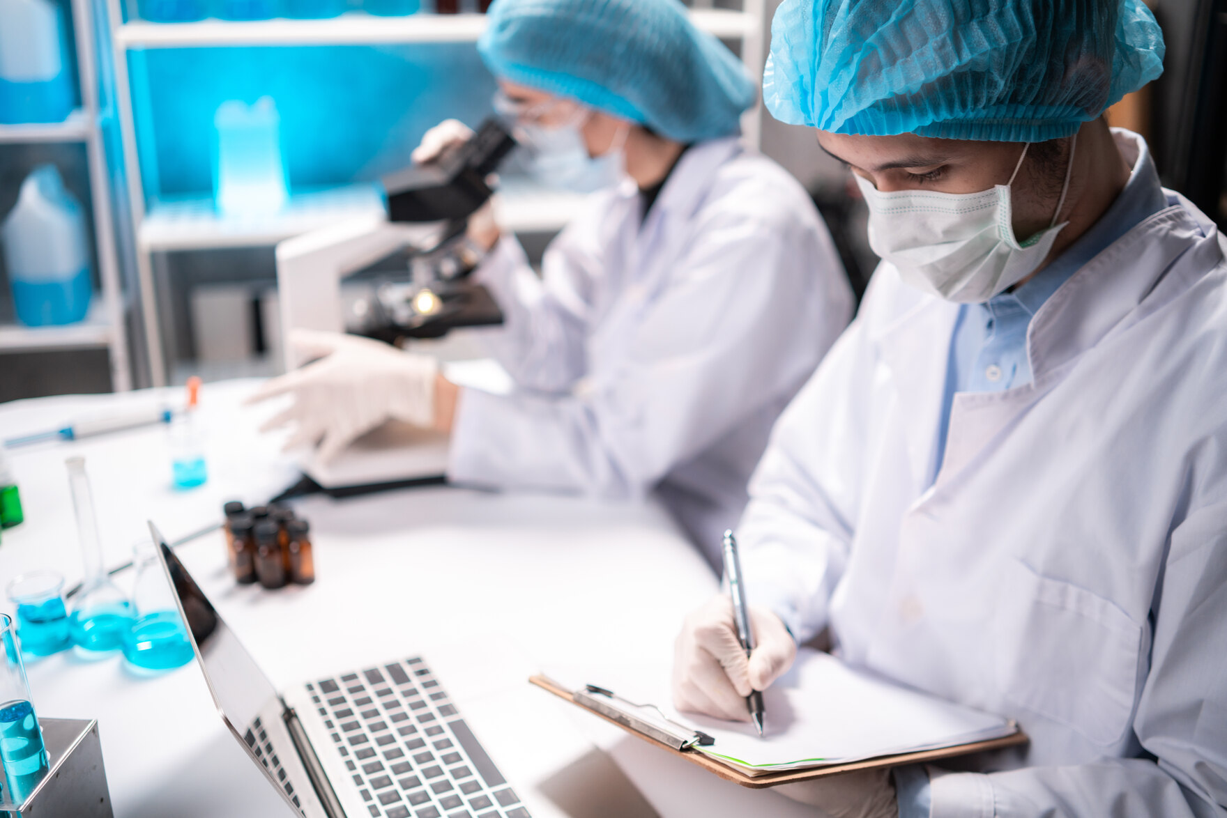 Zwei Wissenschaftler arbeiten mit Mikroskop und Laptop im Labor.