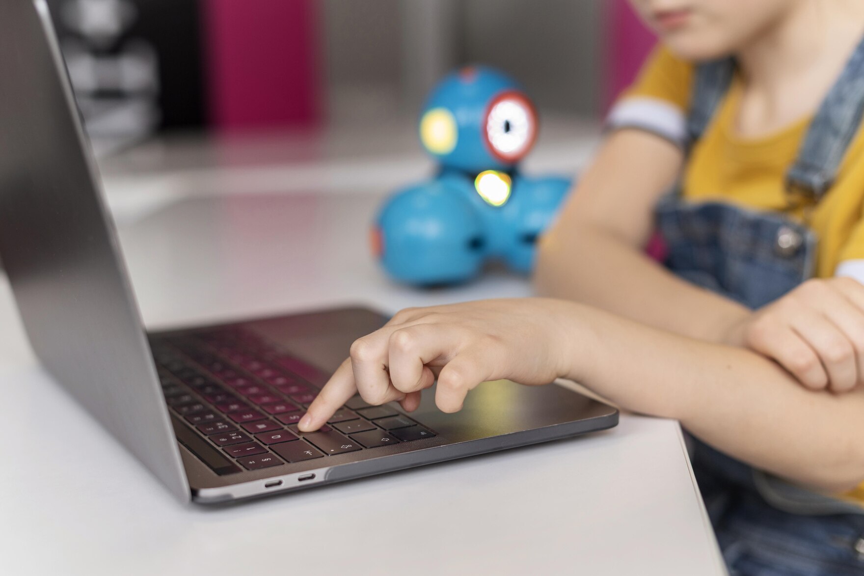 Ein Kind tippt mit dem linken Zeigefinger auf die Tastatur eines Notebooks.