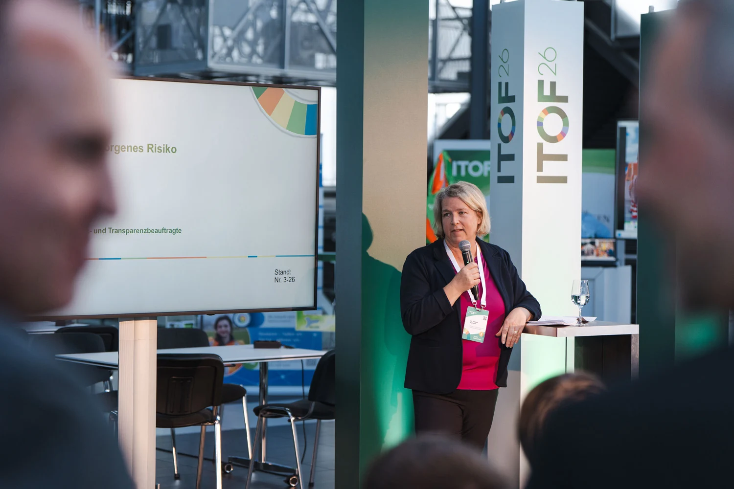 Dr. Juliane Hundert steht neben einem großem Monitor und hält ihren Impulsvortrag auf dem ITOF 2026. 
