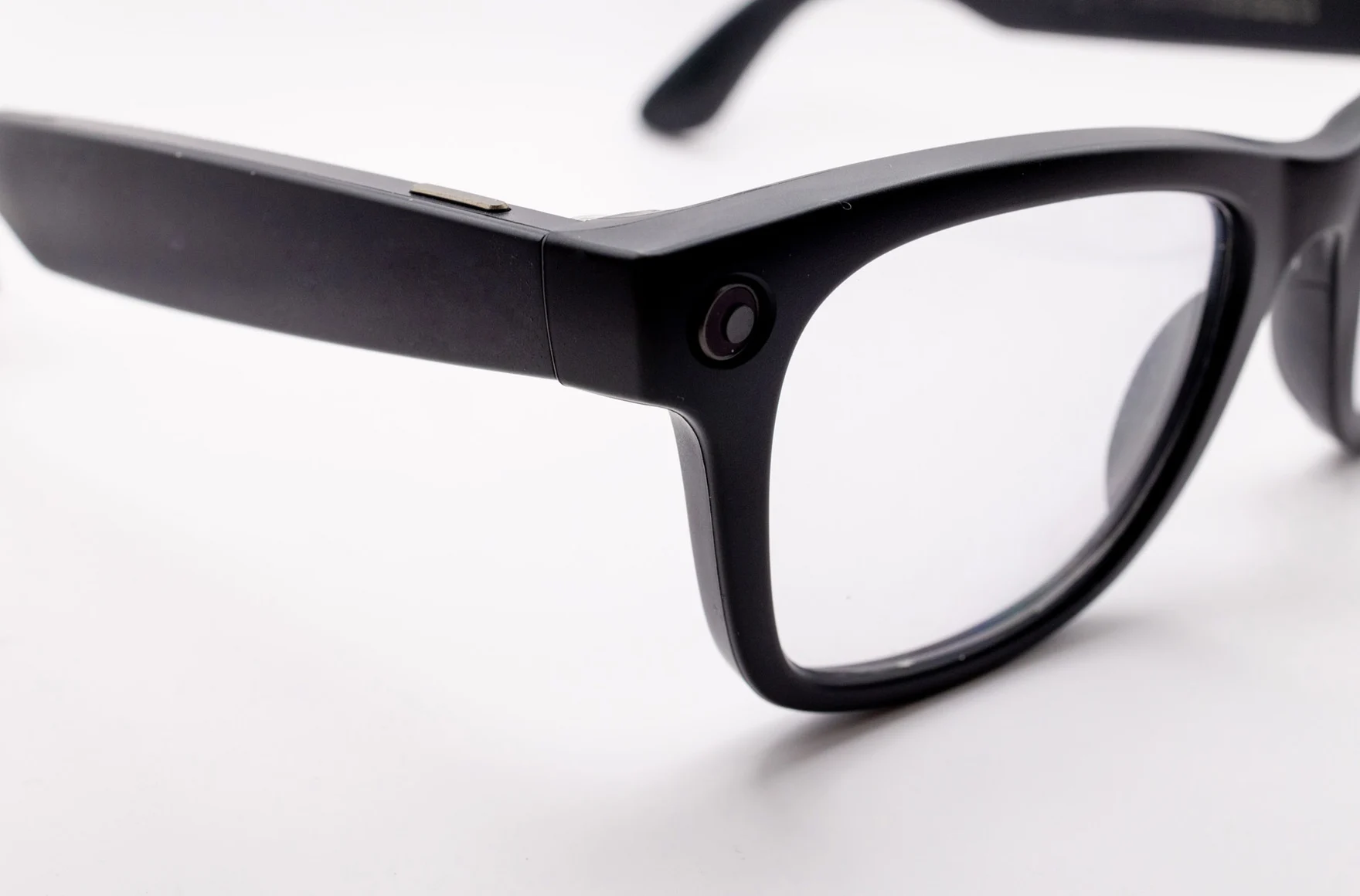 Eine dunkle Brille mit integrierter Kamera am Bügel liegt auf einer hellen Oberfläche.