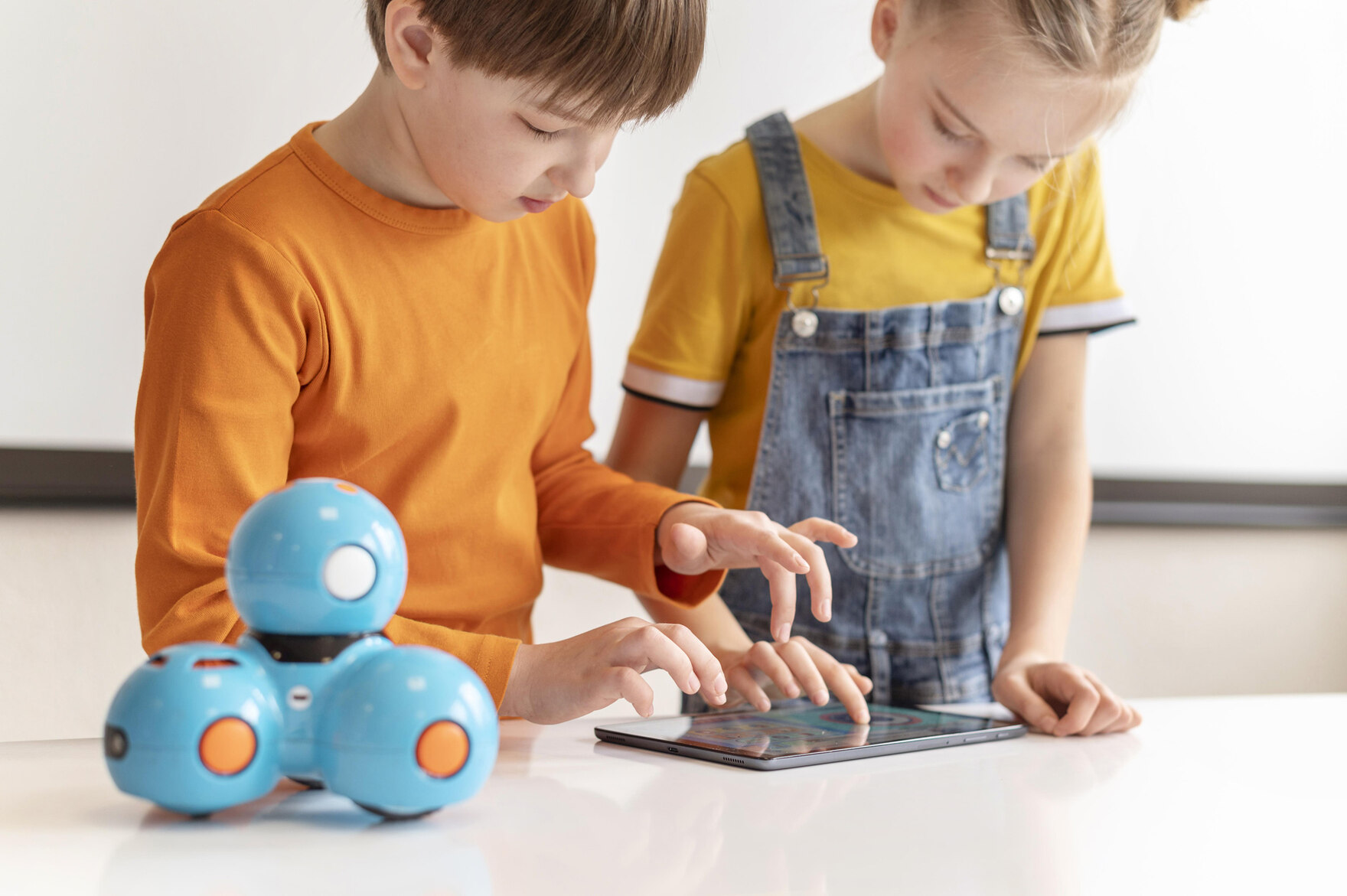 Zwei Kinder bedienen ein Tablet zur Steuerung eines Spielzeugs