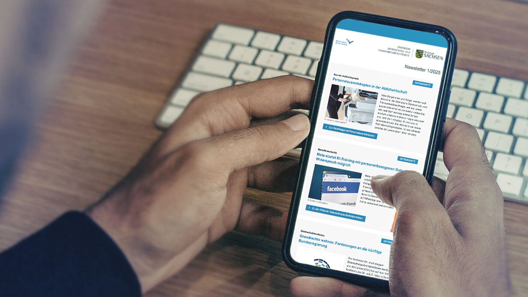 In zwei Händen gehaltenes Smartphone mit Anzeige des Newsletters