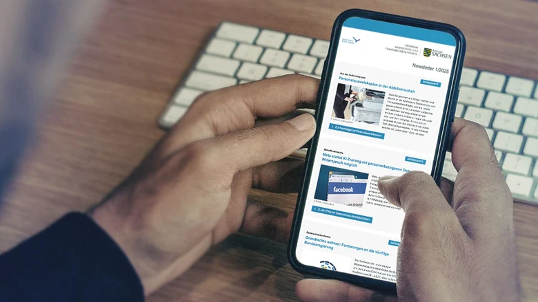 In zwei Händen gehaltenes Smartphone mit Anzeige des Newsletters